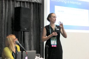 Kate Ervin speaking in front of a screen with a powerpoint slide about becoming a member of a professional organization