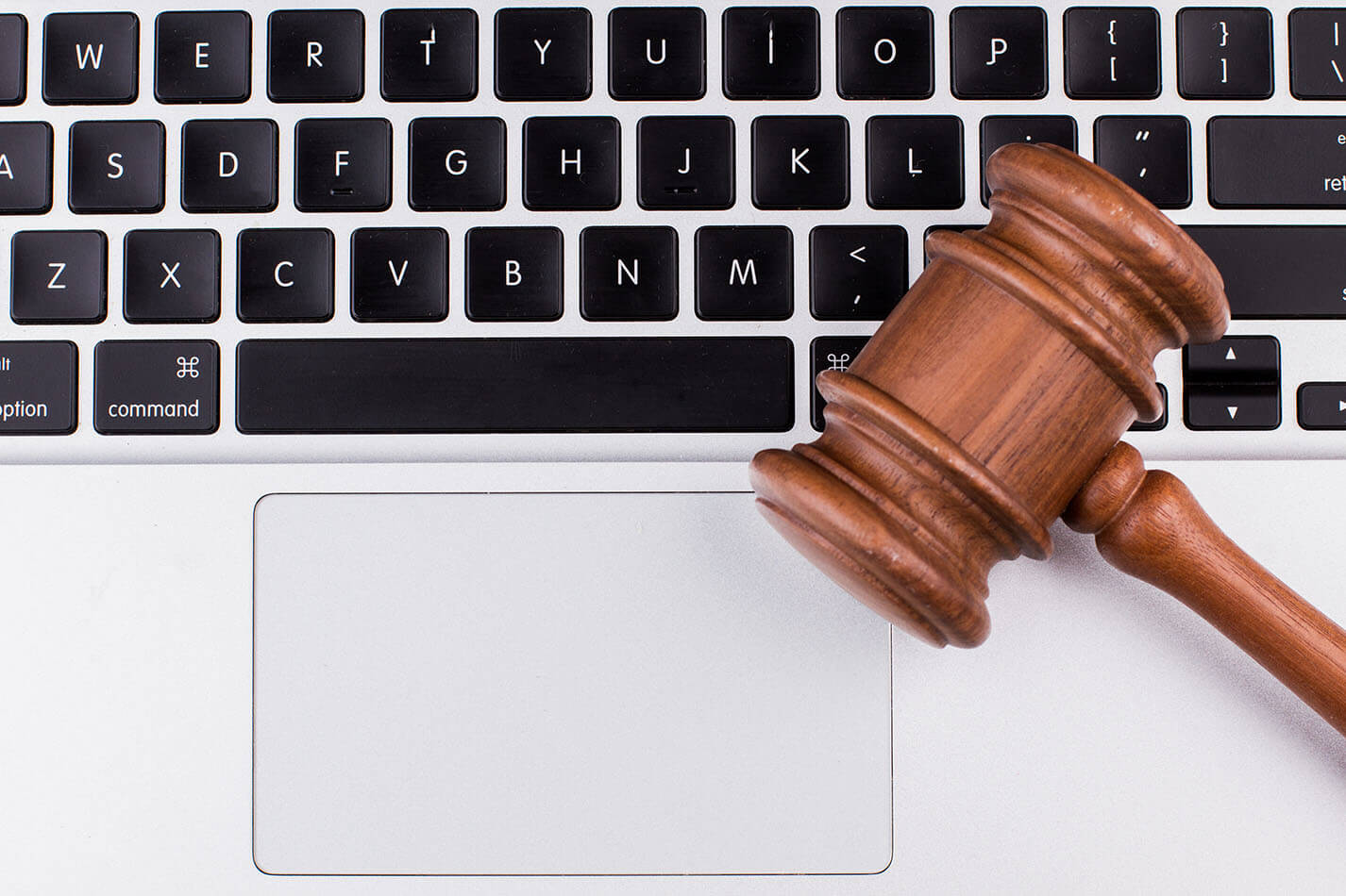 Laptop computer with legal court gavel on keyboard.