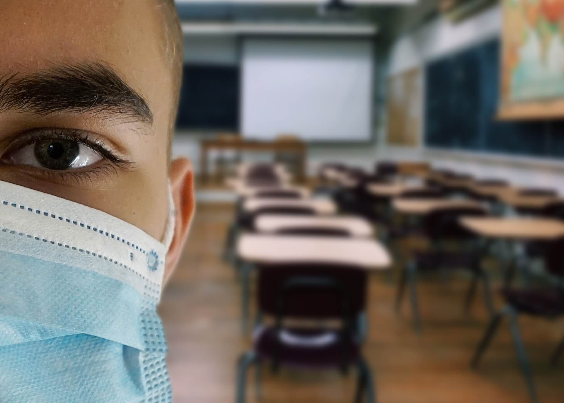man in an empty classroom wearing a surgical mask like those worn during the coronavirus pandemic