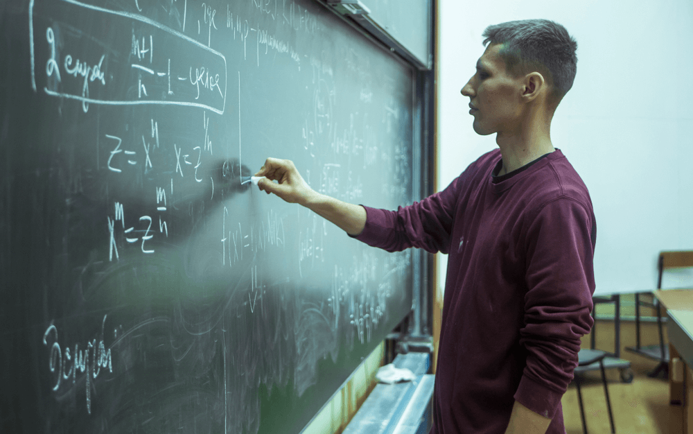 side profile of a teacher at a chalkboard with science equations